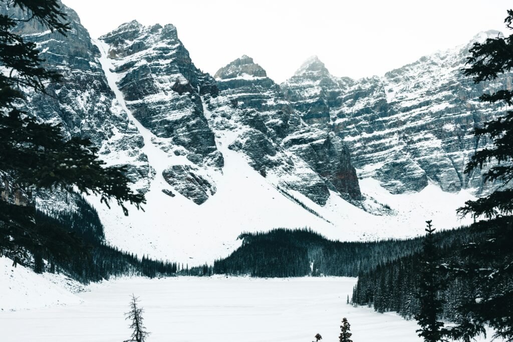 Snowy mountain peaks and frozen lake in Banff National Park create a serene winter landscape.