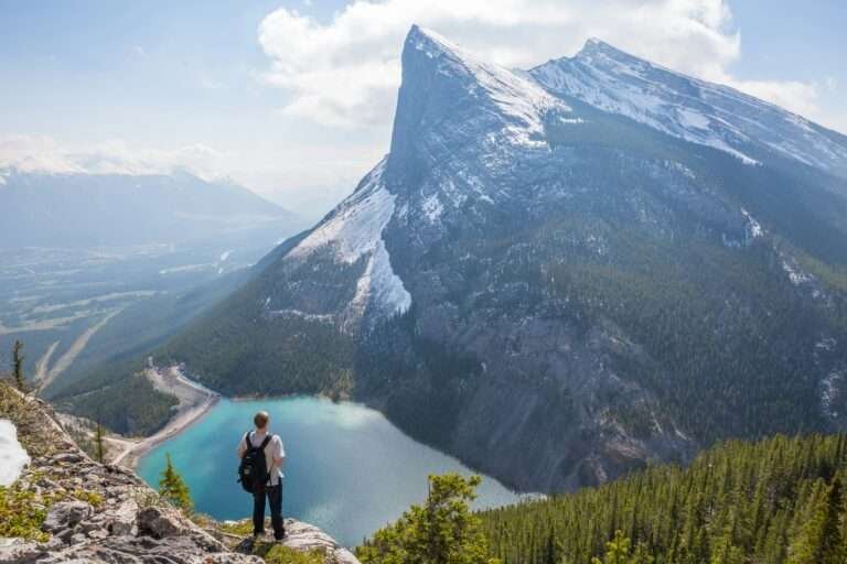 a guy is posing in front of a lake. It is on the hike from Lake Louise, Alberta, Canada