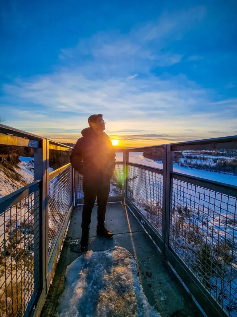 A guy is posing in Keillor point in Edmonton at the afternoon. There is a sunset behind the guy.