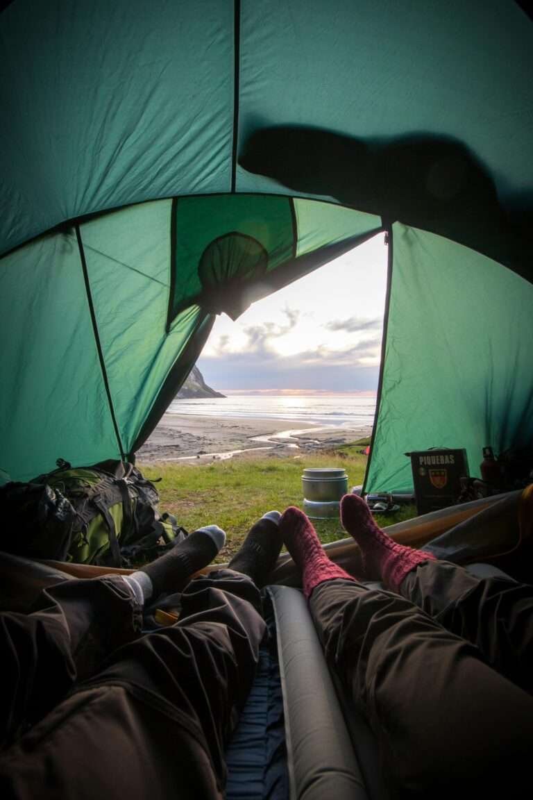 Two people camping in a tent beside a lake.