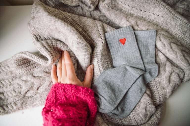 Stay Warm knit sweater with a hand and heart-patterned socks for a cozy winter vibe.