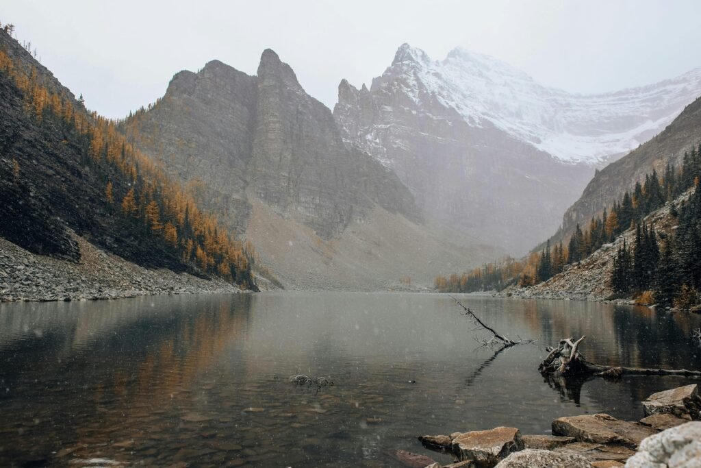 Snow-capped mountains and autumn trees surround Lake Agnes in Alberta, Canada.