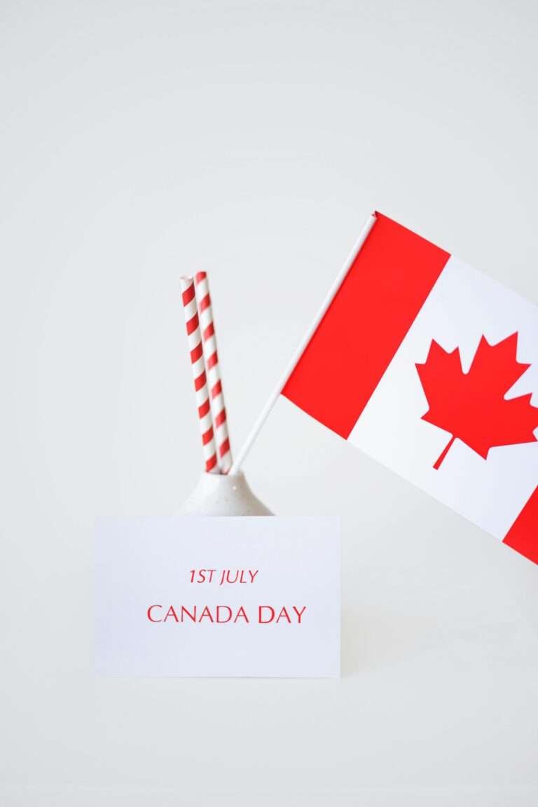 Minimalist Canada Day celebration with flag and festive straws on a white background.