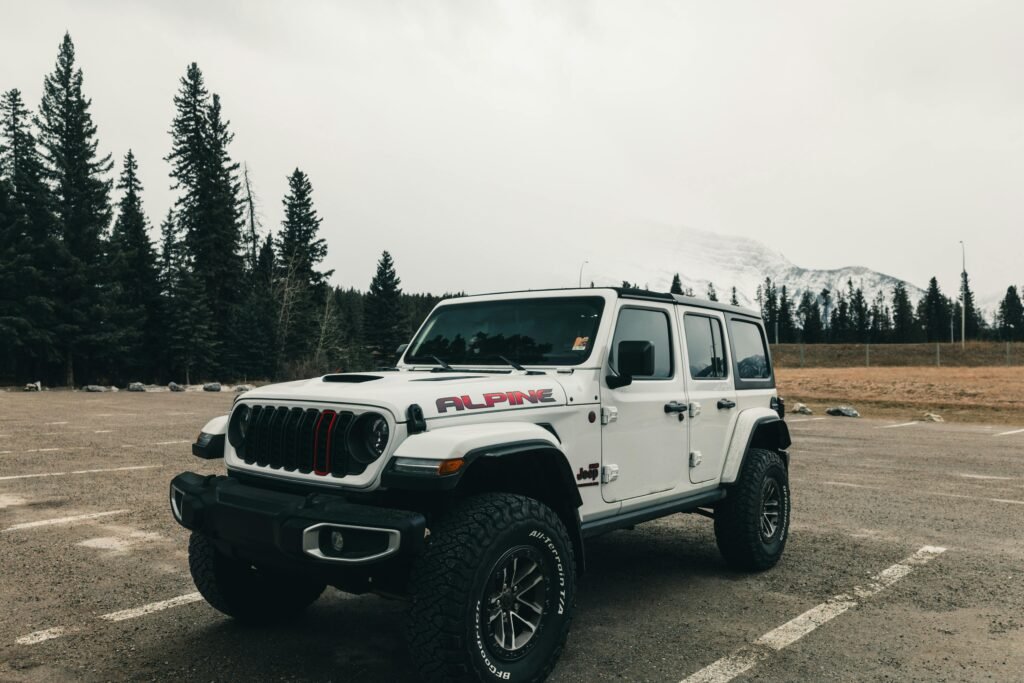 White off-road vehicle parked in Banff National Park with snowy mountains in background.