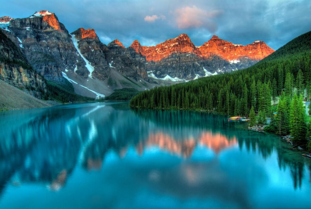 Turquoise alpine lake reflecting rugged mountain peaks at sunrise in the Canadian Rockies, illustrating the dramatic scenery often compared in Banff vs Jasper travel guides.