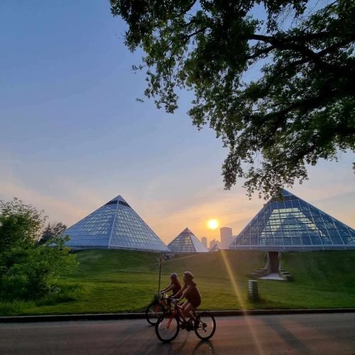 Two persons are riding bicycles at afternoon beside Muttart Conservatory in Edmonton